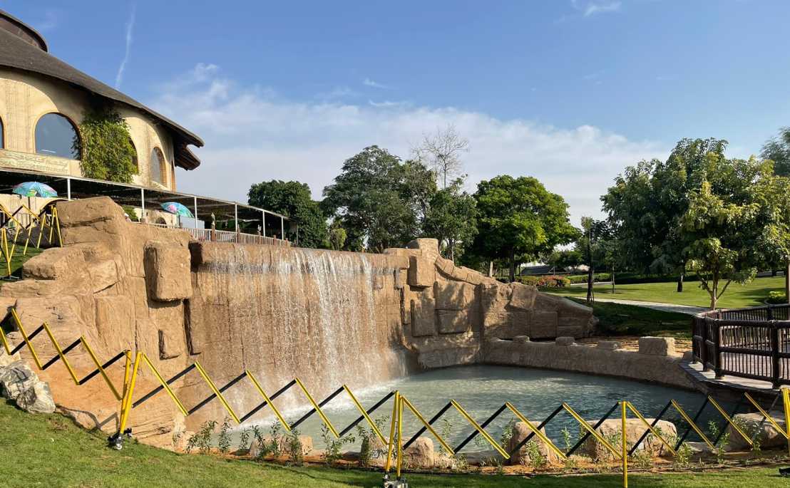 Artificial rock waterfall flowing into a pool at Dubai Safari Park